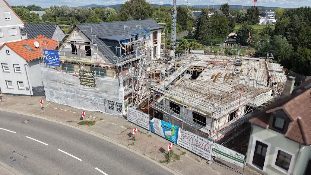 Luftaufnahme einer Baustelle mit Rohbau und Gerüst in einer Ortslage