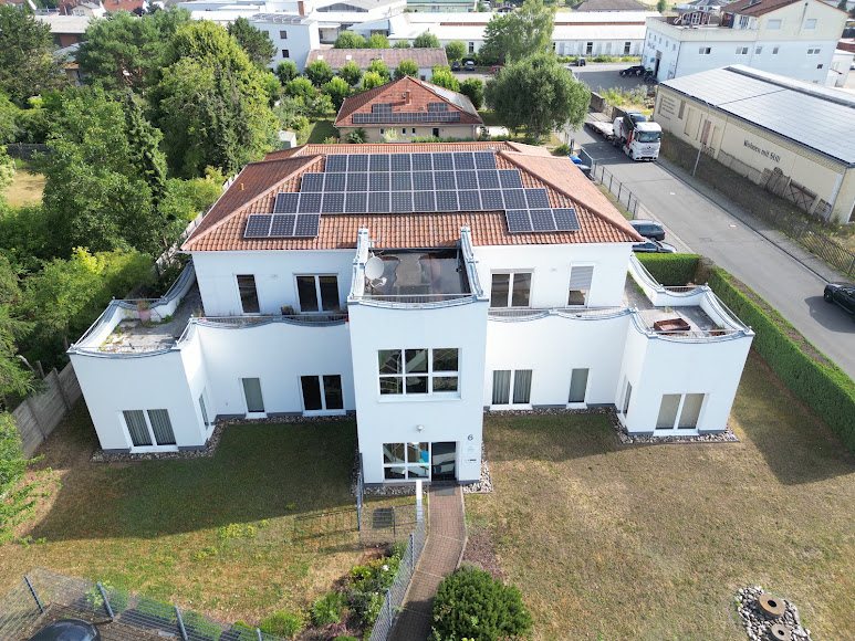 Luftaufnahme eines weißen Gebäudes mit Photovoltaikanlage auf dem Dach